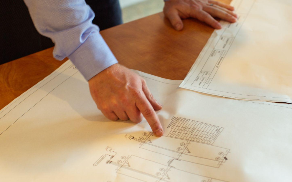 A hand points to a diagram of a wastewater treatment system.