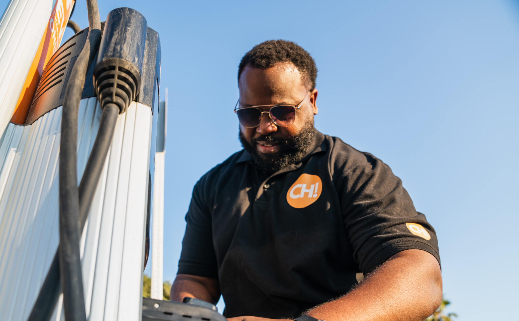 A ChargerHelp! technician works on repairing an electric vehicle charging station.