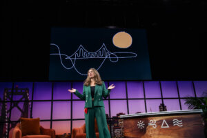 Elemental founder and CEO Dawn Lippert speaks on state at Elemental Interactive 2024, in front of an artful drawing of a bridge.