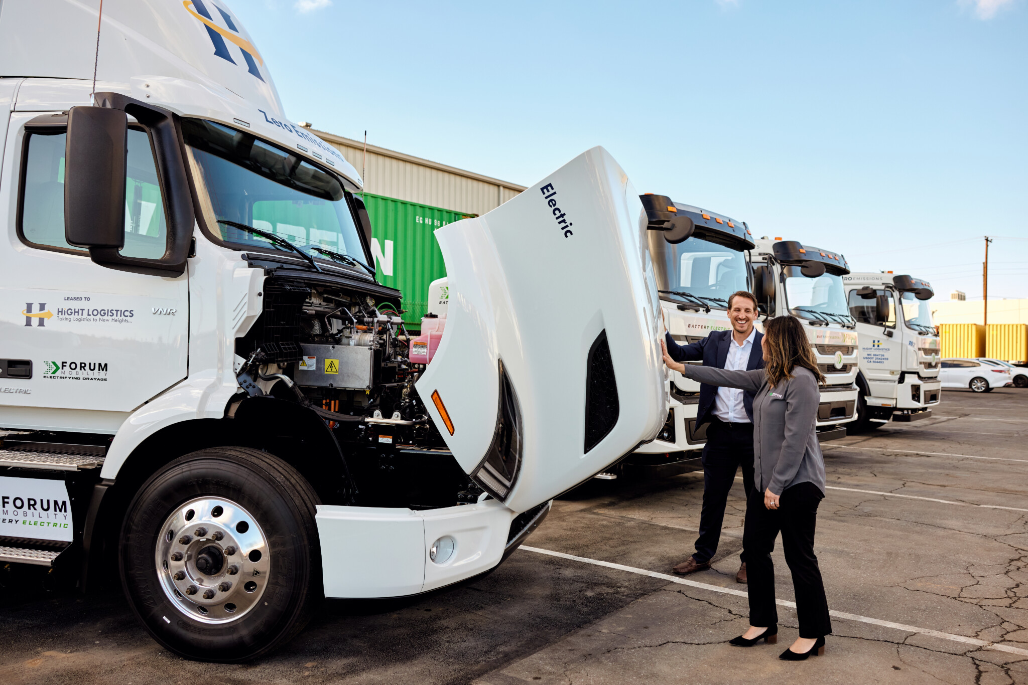 Two Forum Mobility employees stand beside a heavy duty electric truck.