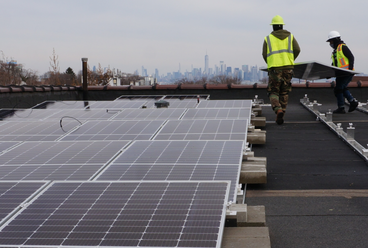 Clean energy workers install solar panels on a rooftop in New York City.