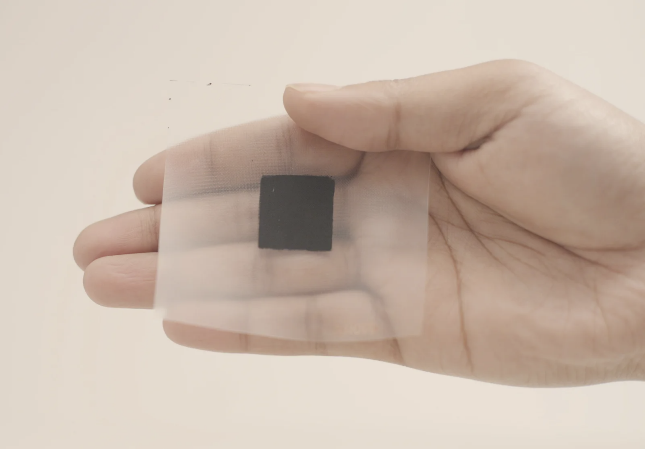 A closeup of a hand a shiny black leaf square that is used to turn CO2 into chemicals